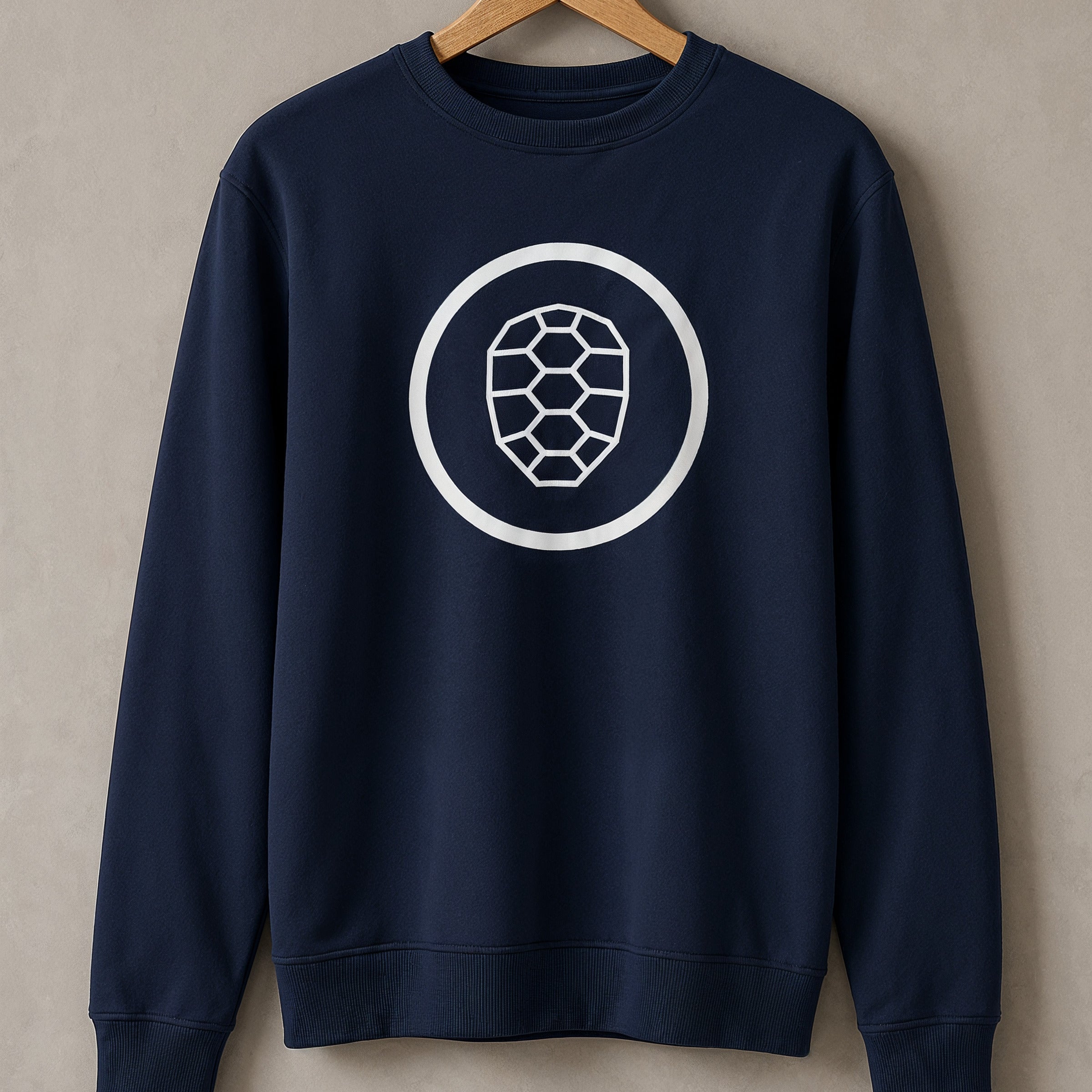 Navy ONETURTLE sweatshirt on a wooden hanger against the studio wall
