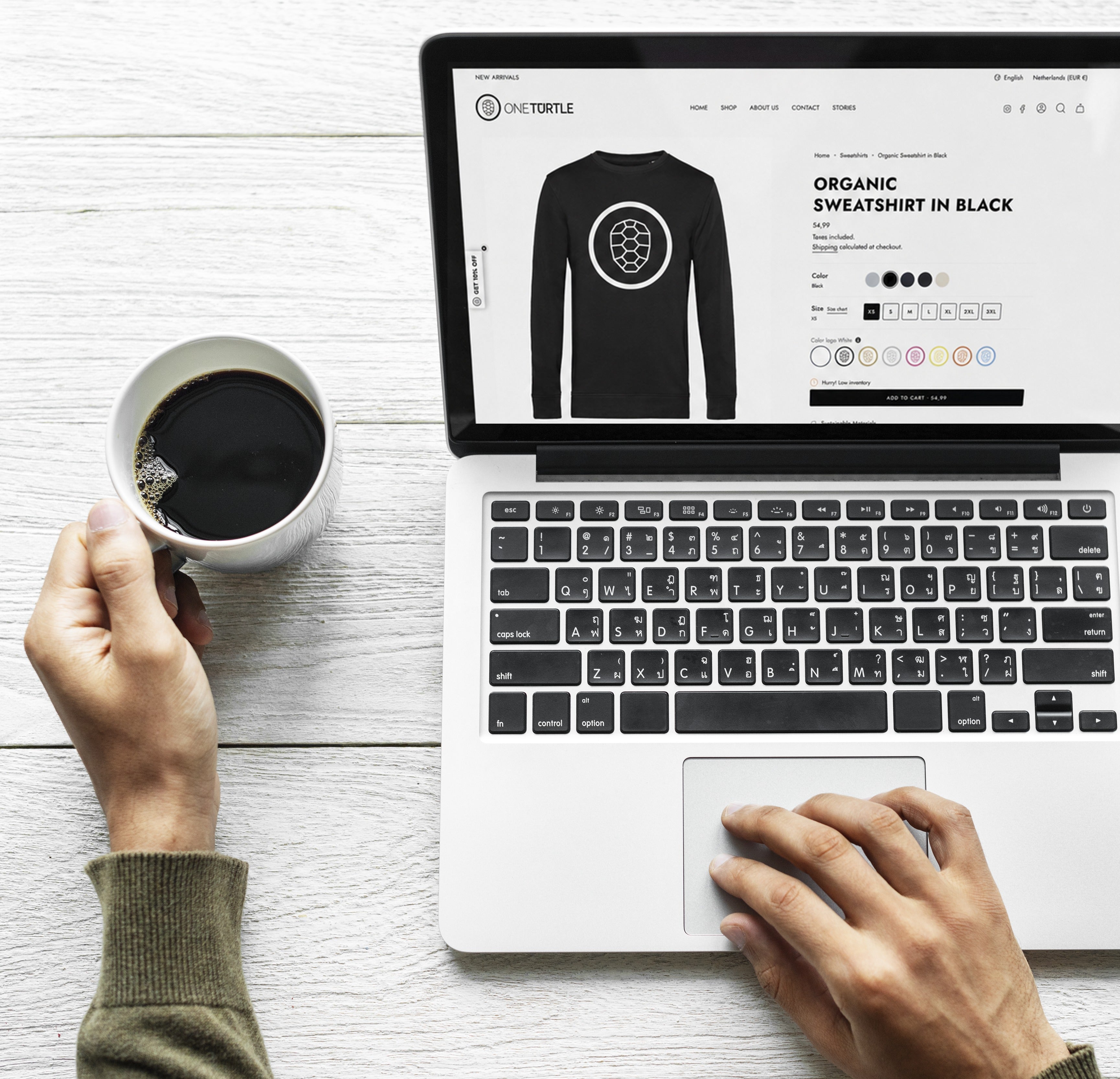 Ordering a custom ONETURTLE sweatshirt on a laptop, choosing color, size and logo
