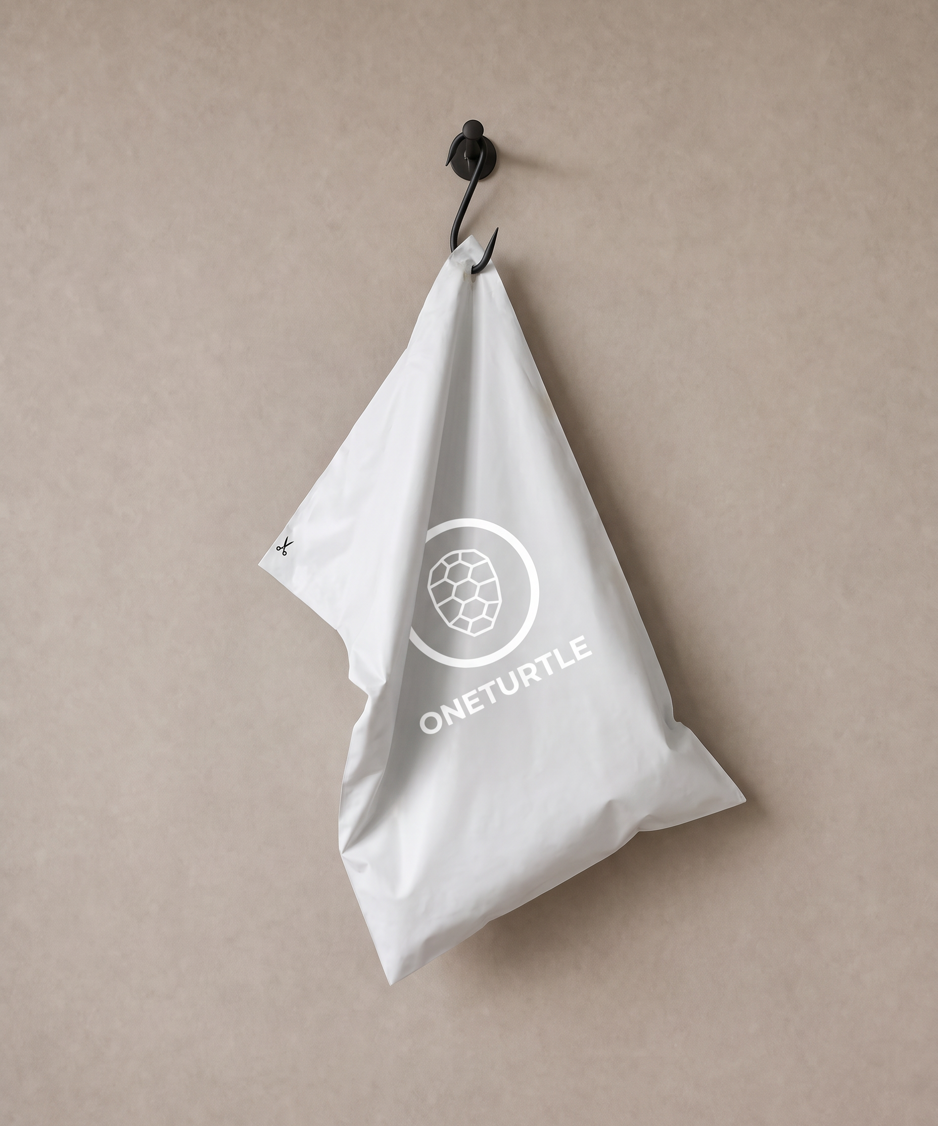 ONETURTLE compostable mailer bag hanging on a metal hook against the studio wall