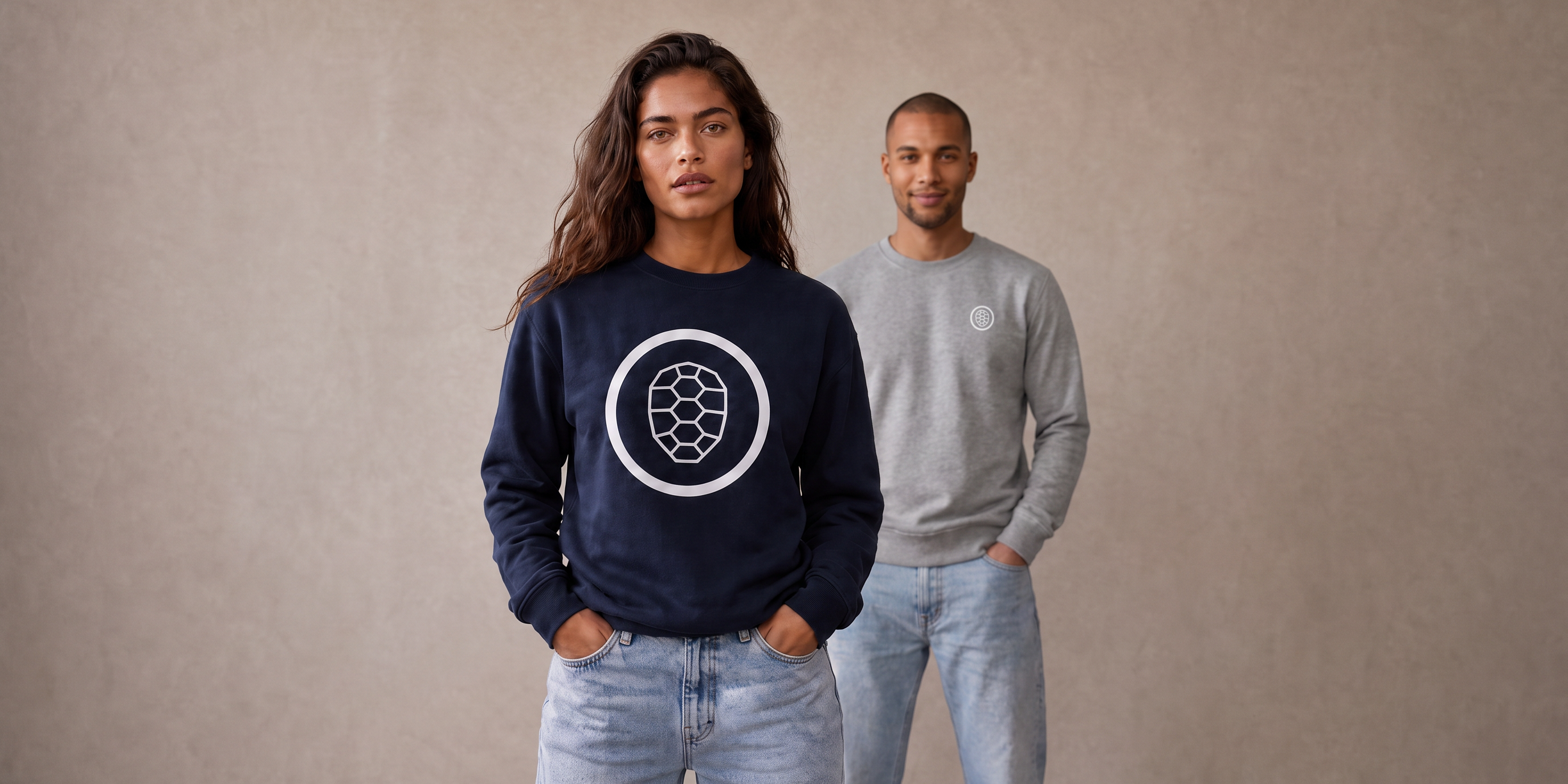 Vera in navy ONETURTLE sweatshirt in front, Noah in grey sweatshirt behind her, studio