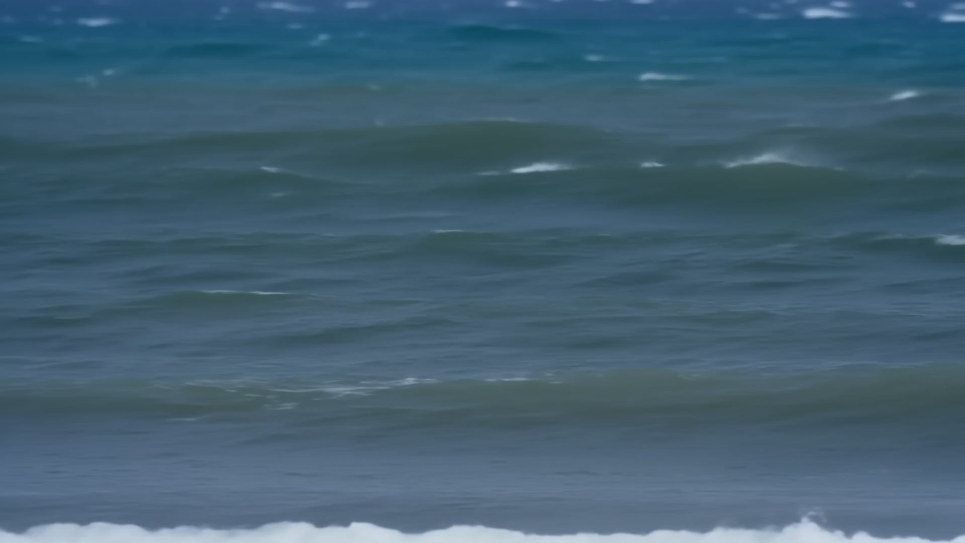 Vera windsurfing at full speed across choppy water, planing on a white board with the dark ONETURTLE sail