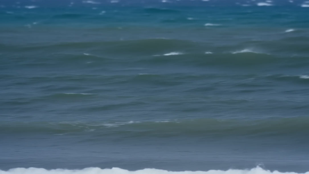 Vera windsurfing at full speed across choppy water, planing on a white board with the dark ONETURTLE sail